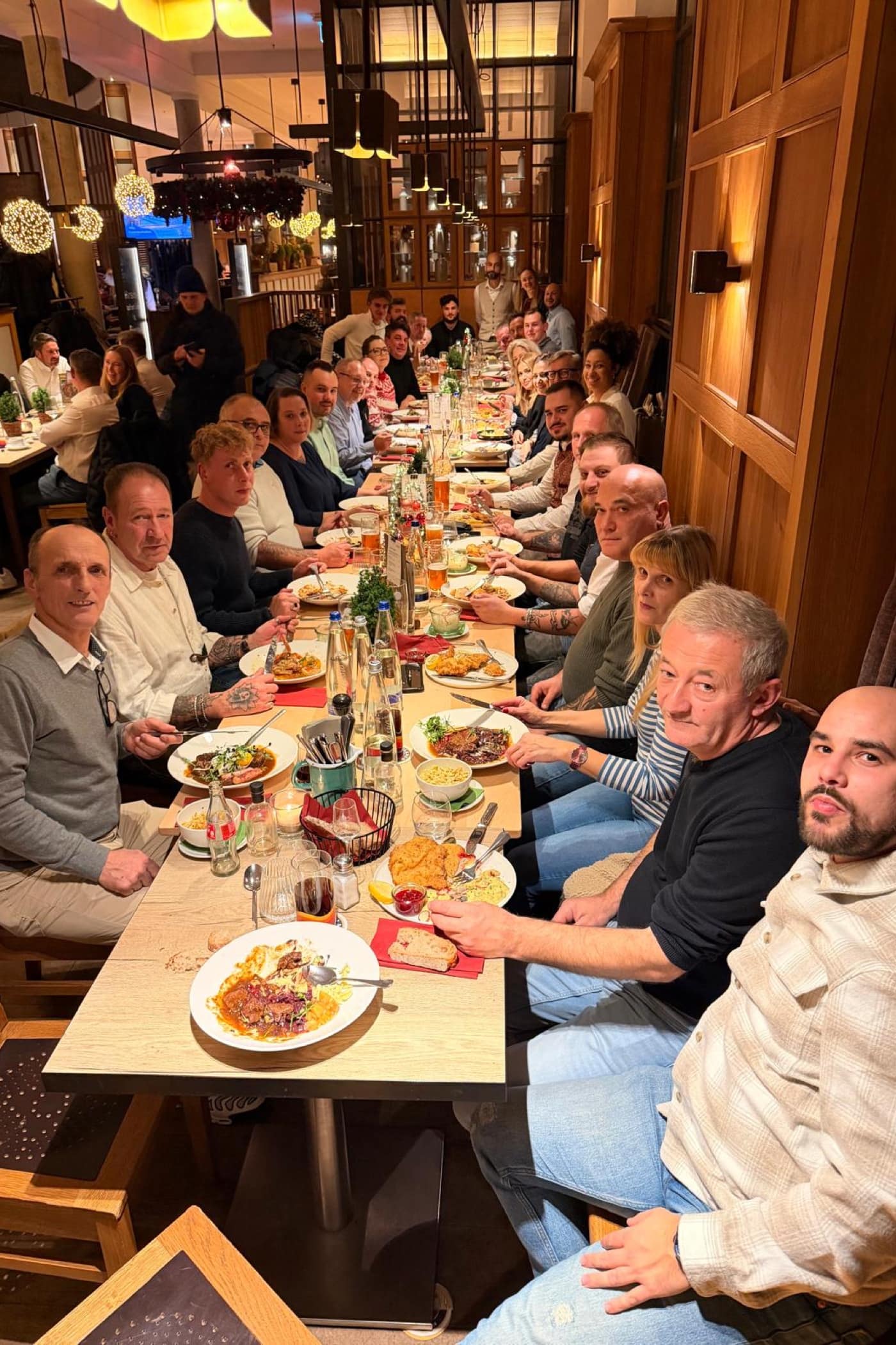 Mitarbeiter bei Weihnachtsessen 2025 an Tisch Hochformatfoto